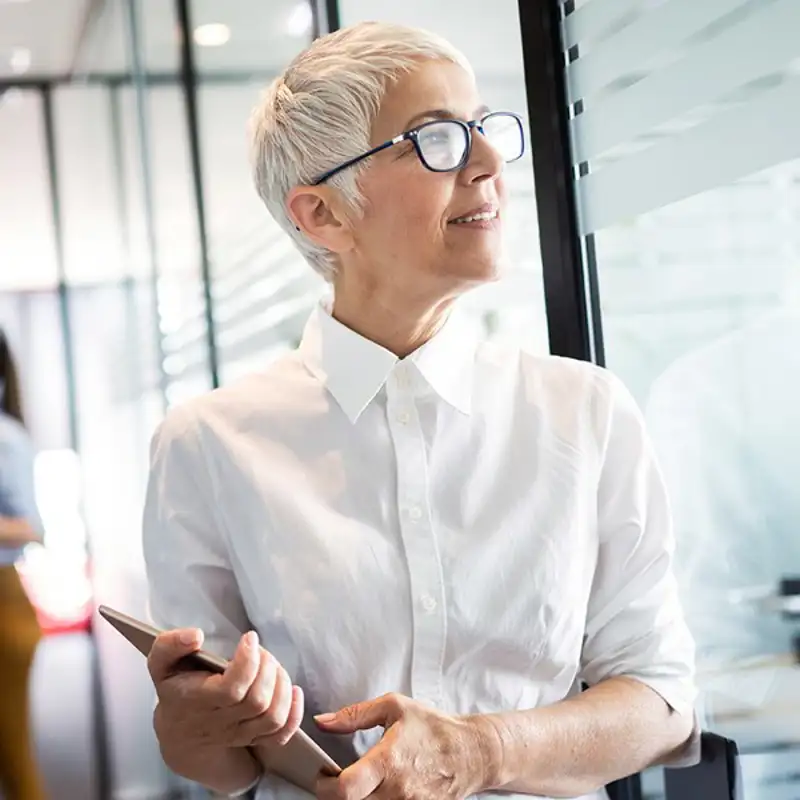 Older woman walking through office with her tablet.