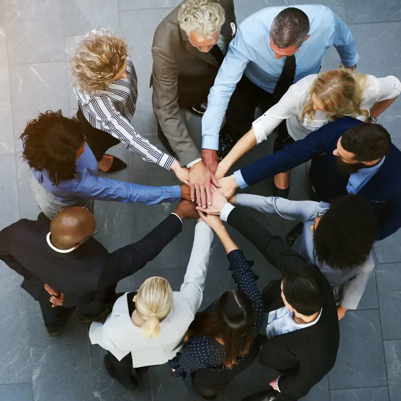 aerial view of diverse coworkers with hands on hands.