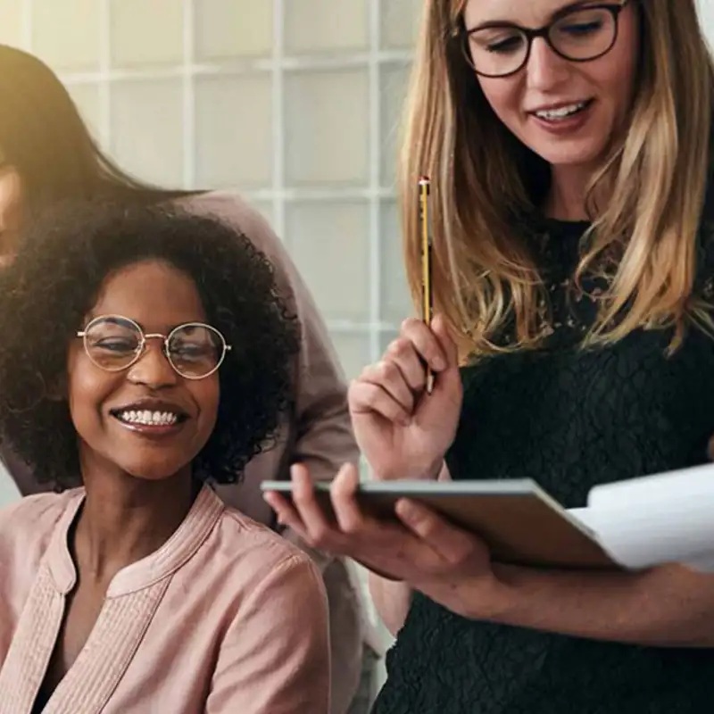 Group of female coworkers looking at paperwork laughing.