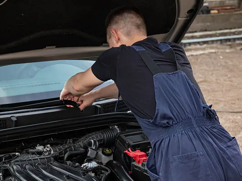 A mechanic works on a vehicle with its bonnet up